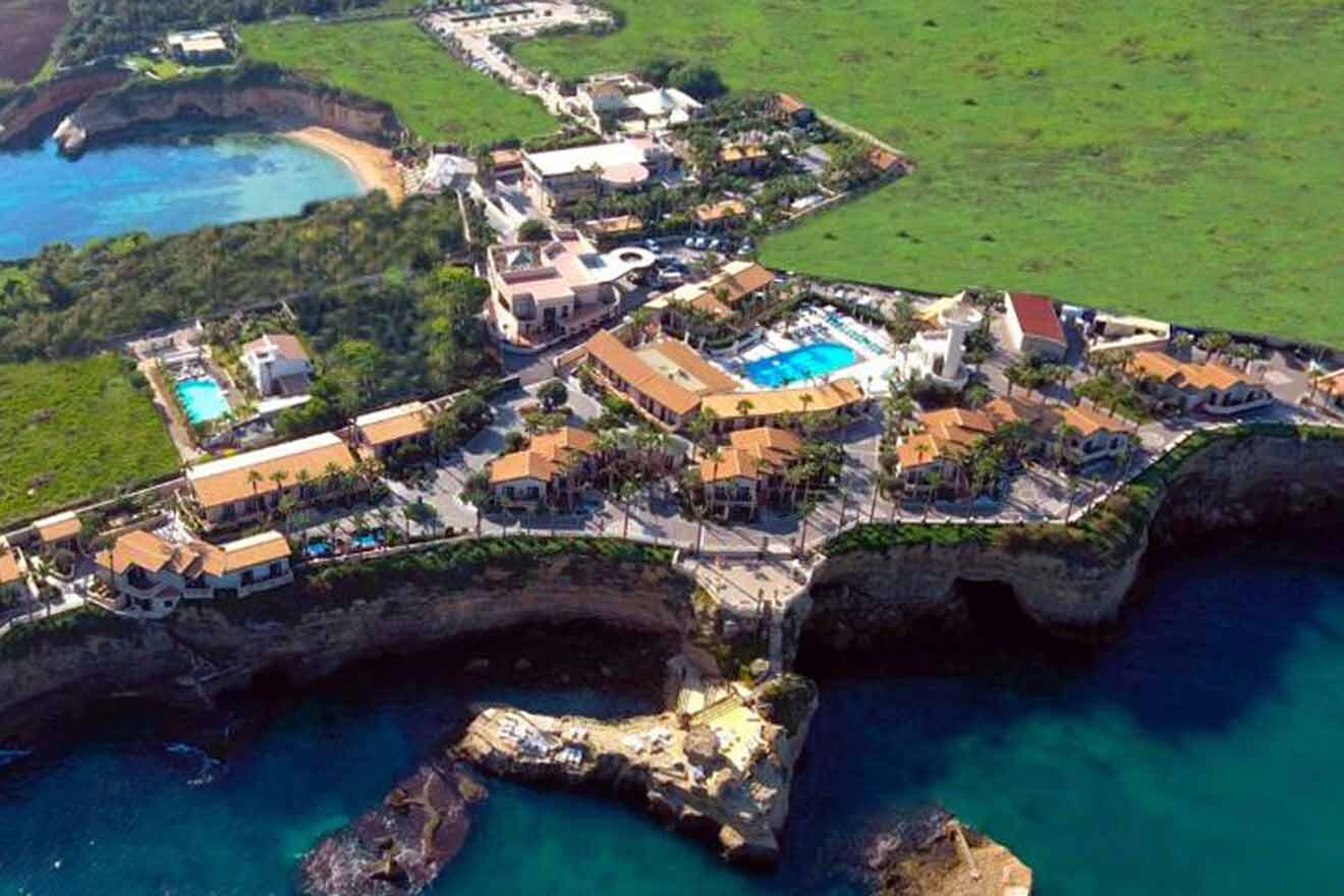 A bird's eye view of a resort on a cliff overlooking the ocean.