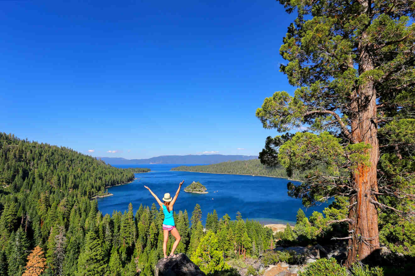 A woman is standing on top of a rock overlooking lake tahoe.