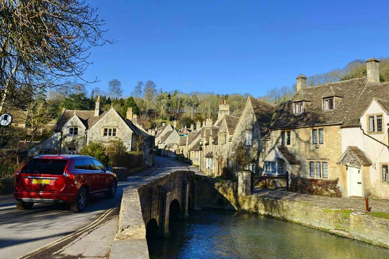 A red car driving down a river in cotswolds.