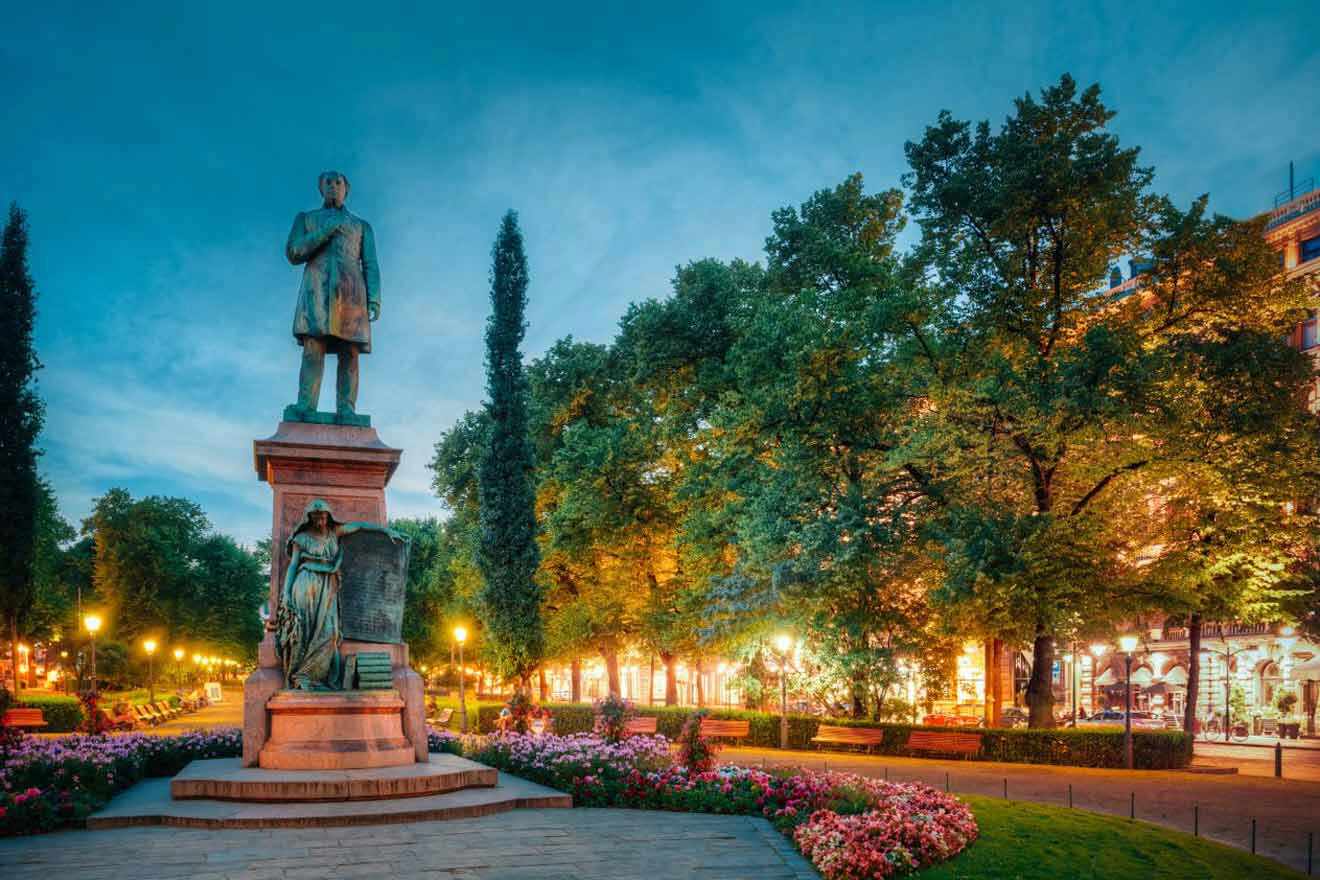 A statue in the middle of a park at dusk.