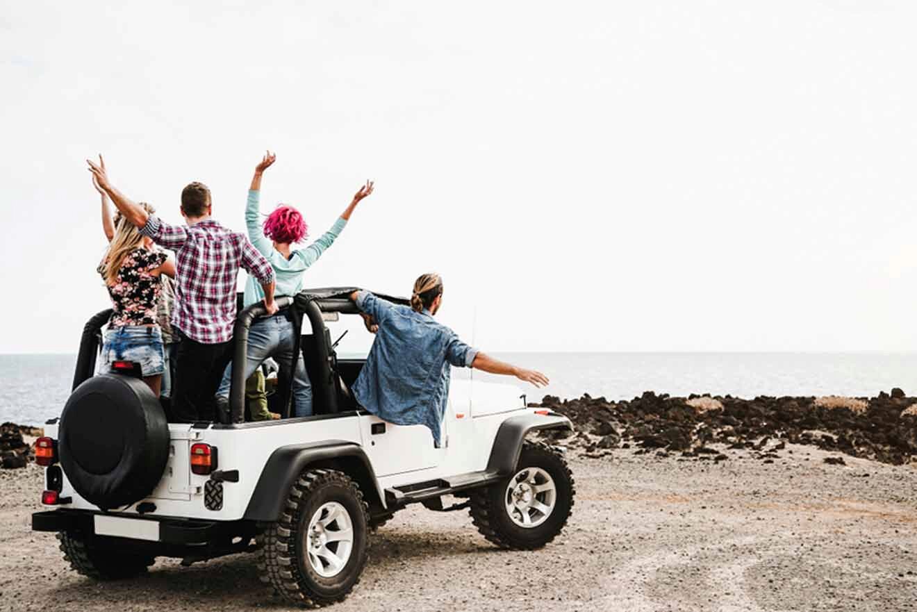 A group of people riding in a jeep on the beach.