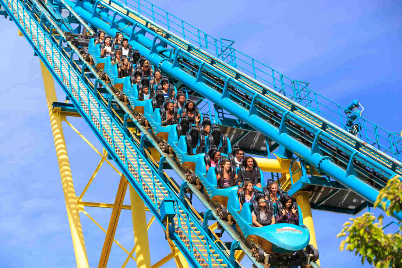 A blue and yellow roller coaster with people riding on it.