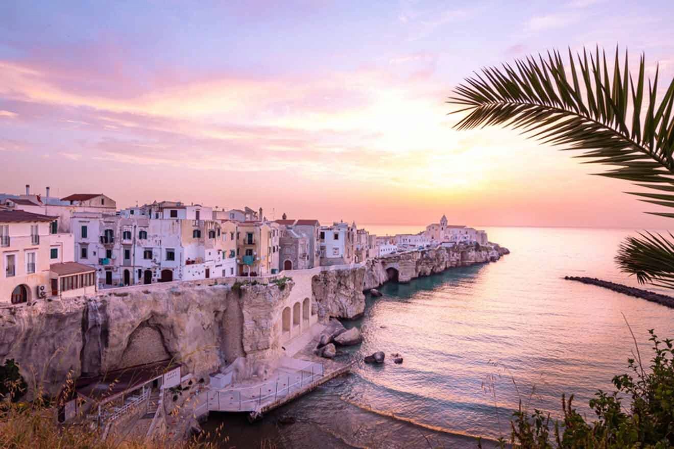 A city at sunset with palm trees and cliffs.