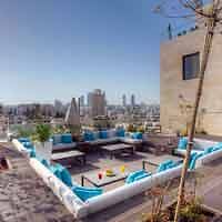 A rooftop patio with blue lounge chairs and a view of the city.