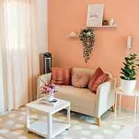 A living room with pink walls and a white couch.