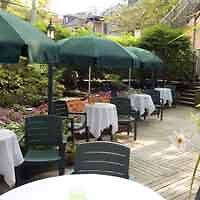A wooden deck with tables and umbrellas.