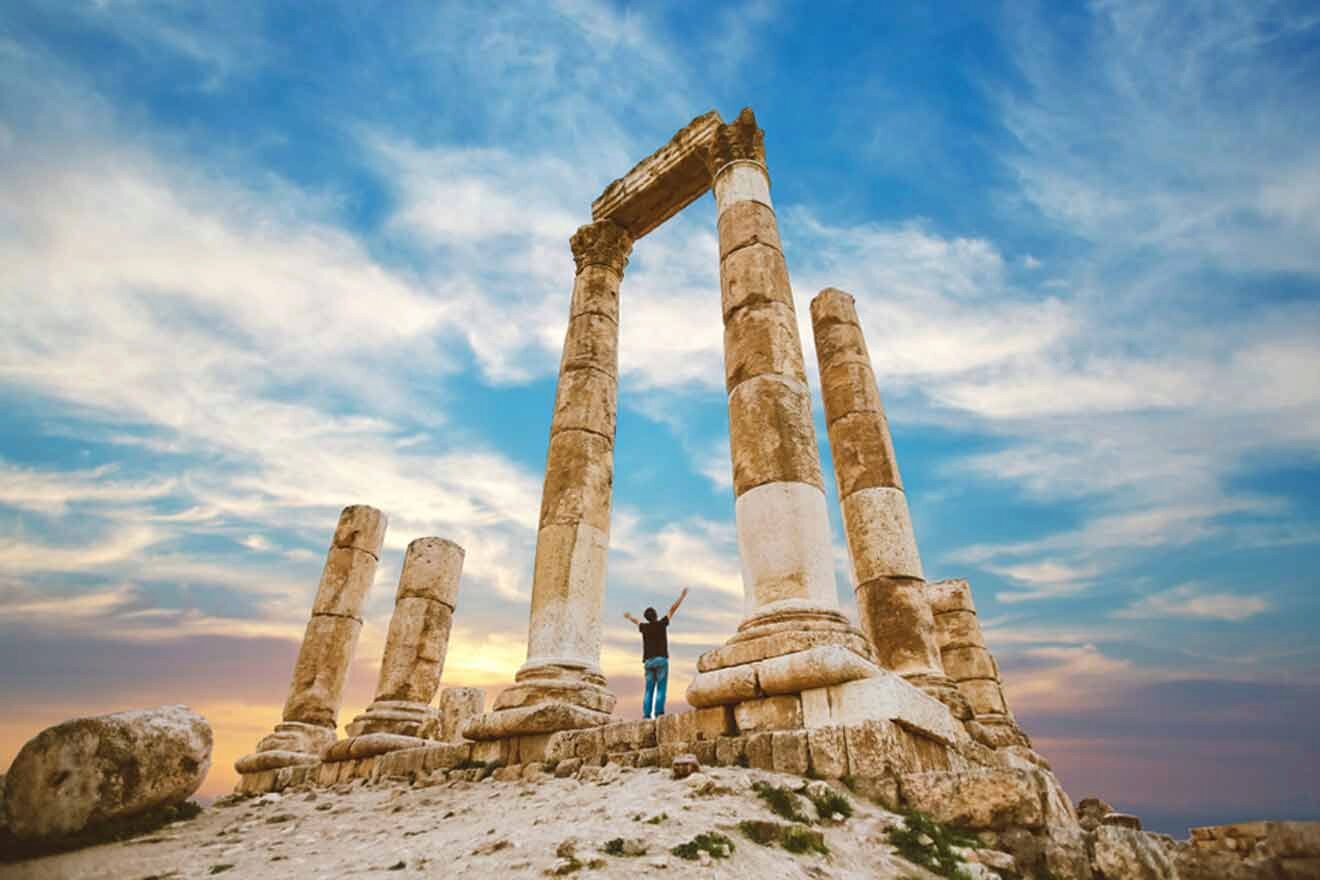 A man is standing on top of a pillar in the amman citadel.
