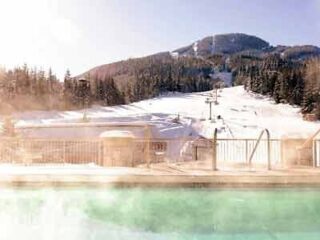 A hot tub in the snow with a mountain in the background.