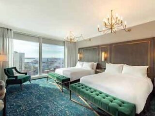 Two beds in a hotel room with a view of the city.