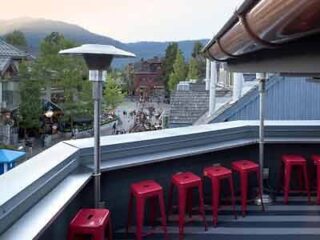 A balcony with red stools and a view of mountains.