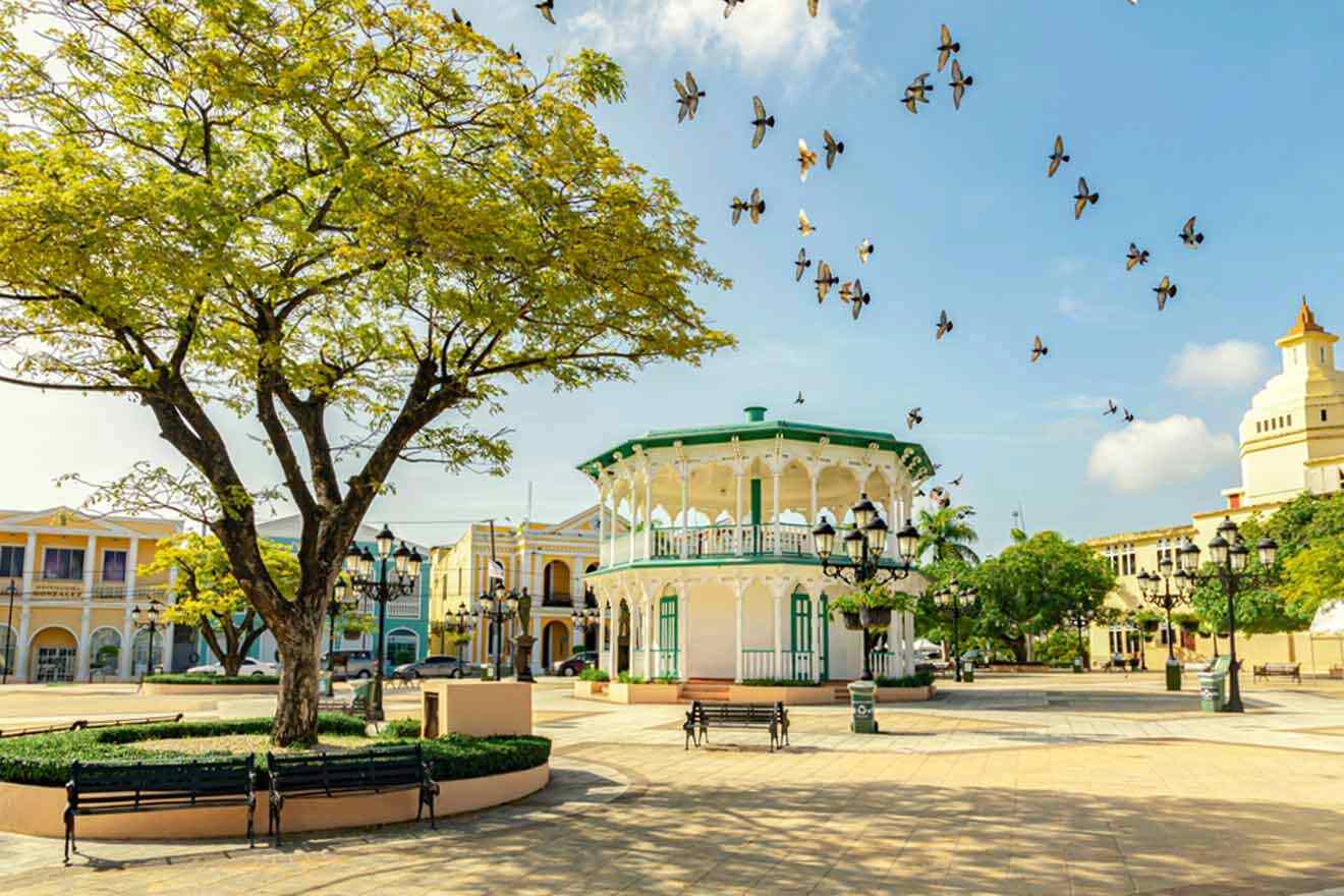 A city with a gazebo and birds flying around it.