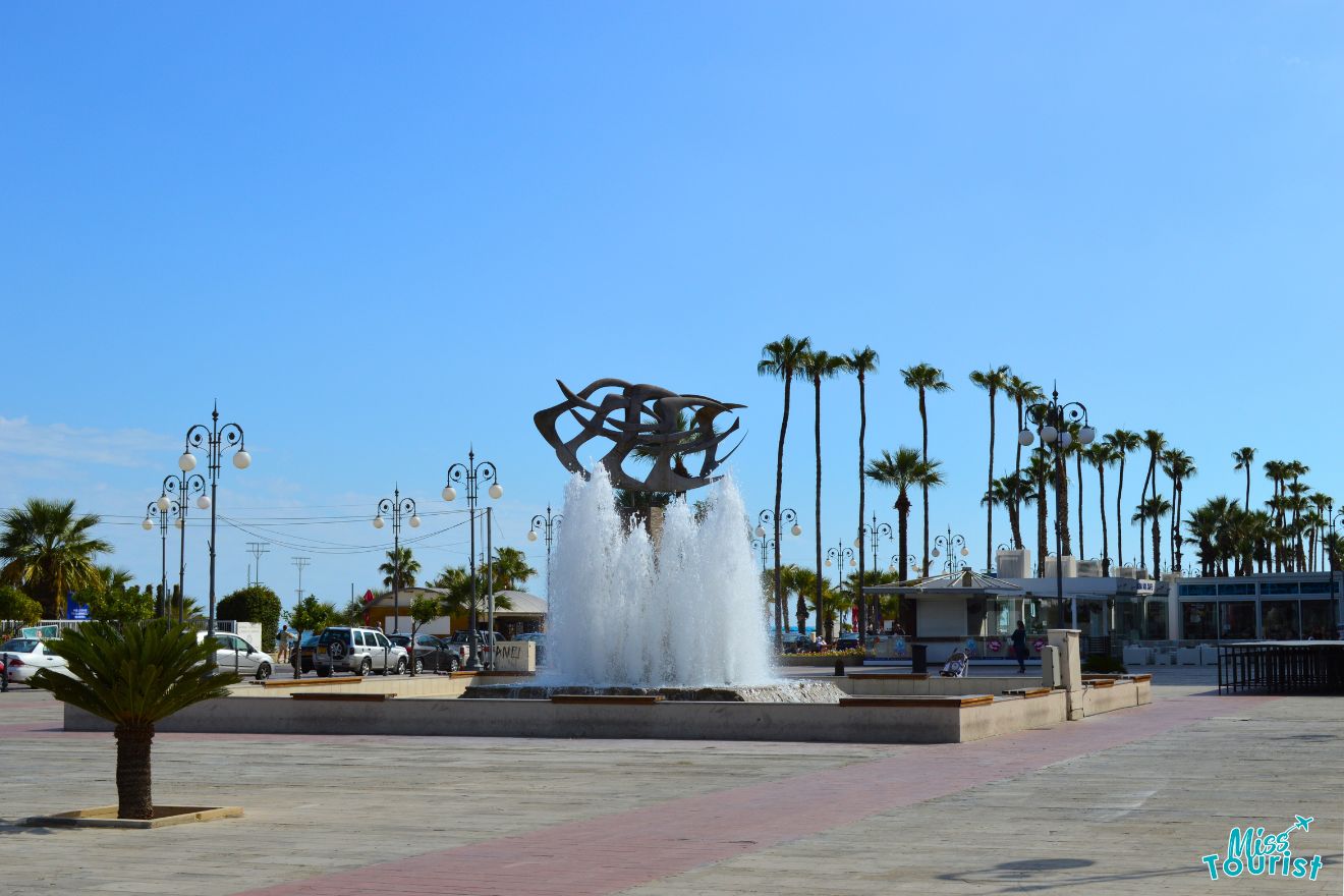 A fountain in the Finikoudes beach plaza with palm trees.