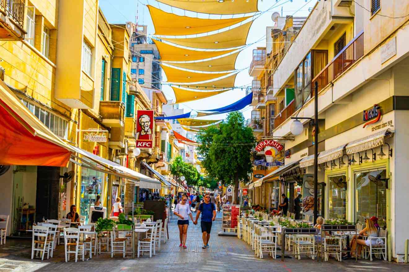 A street in a city with tables and umbrellas.