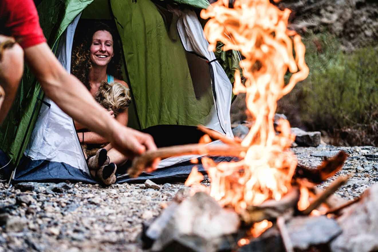 A man and woman sitting next to a campfire in a tent.