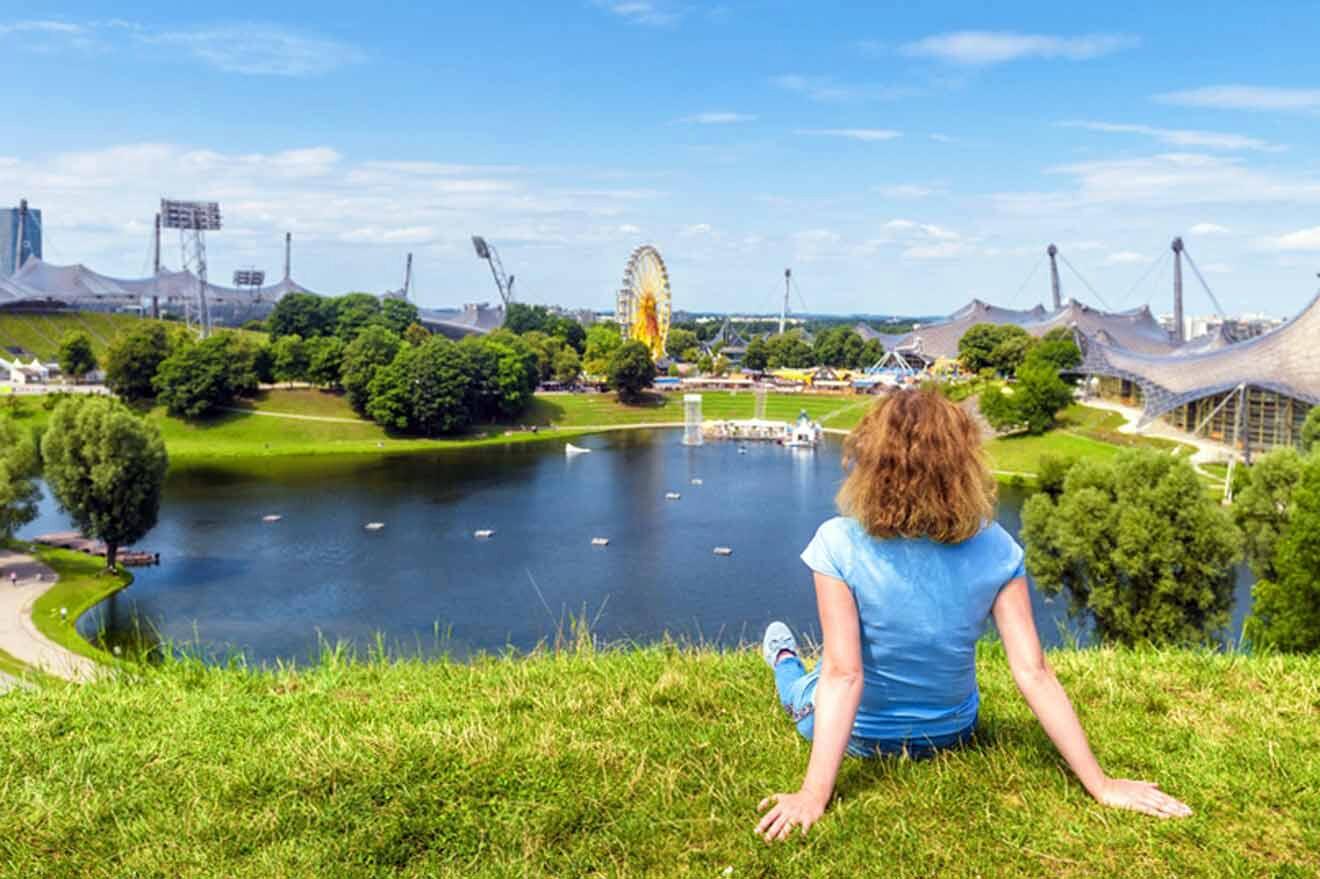A girl sits on the grass overlooking the olympic park.