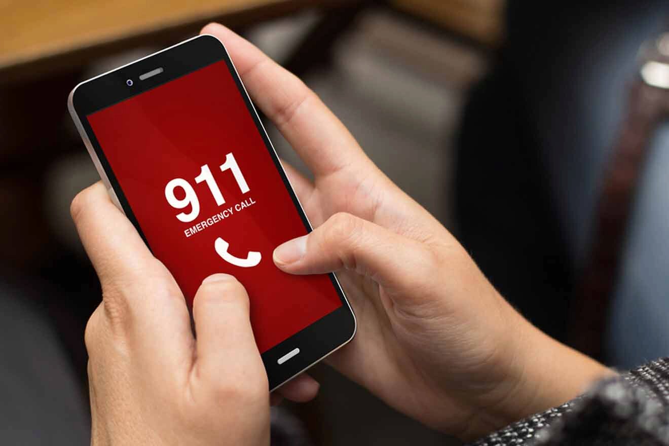 A person holding a phone with a 911 number on it.