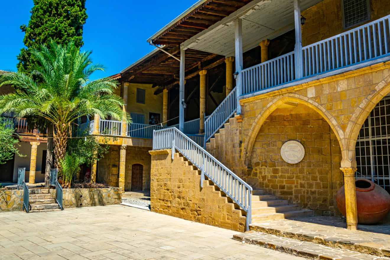 The courtyard of an old building with stairs and palm trees.