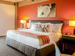 A hotel room with orange walls and a bed.