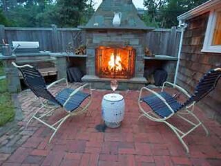 A patio with a fire pit and chairs.
