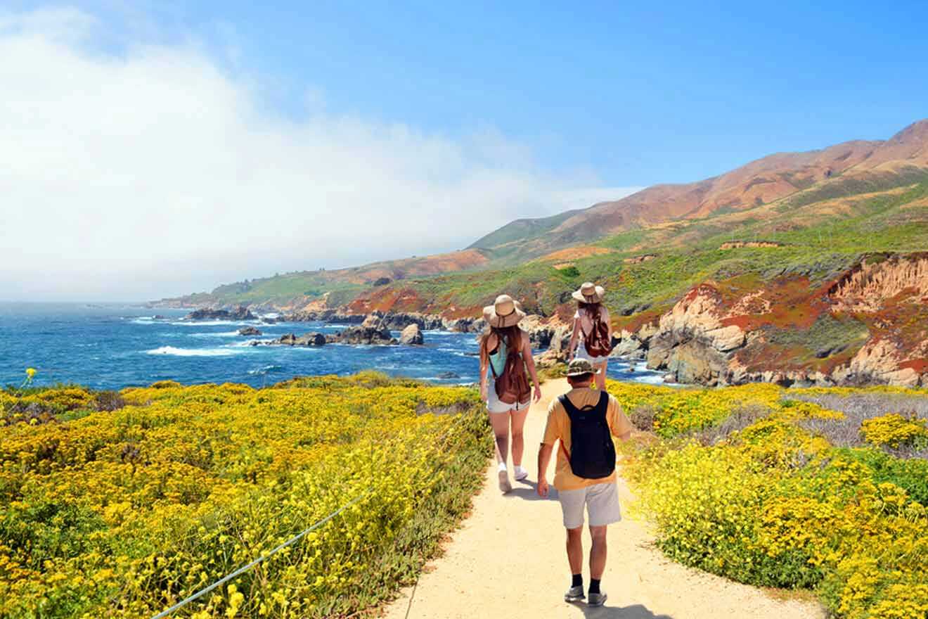 A group of people walking along a path near the ocean.