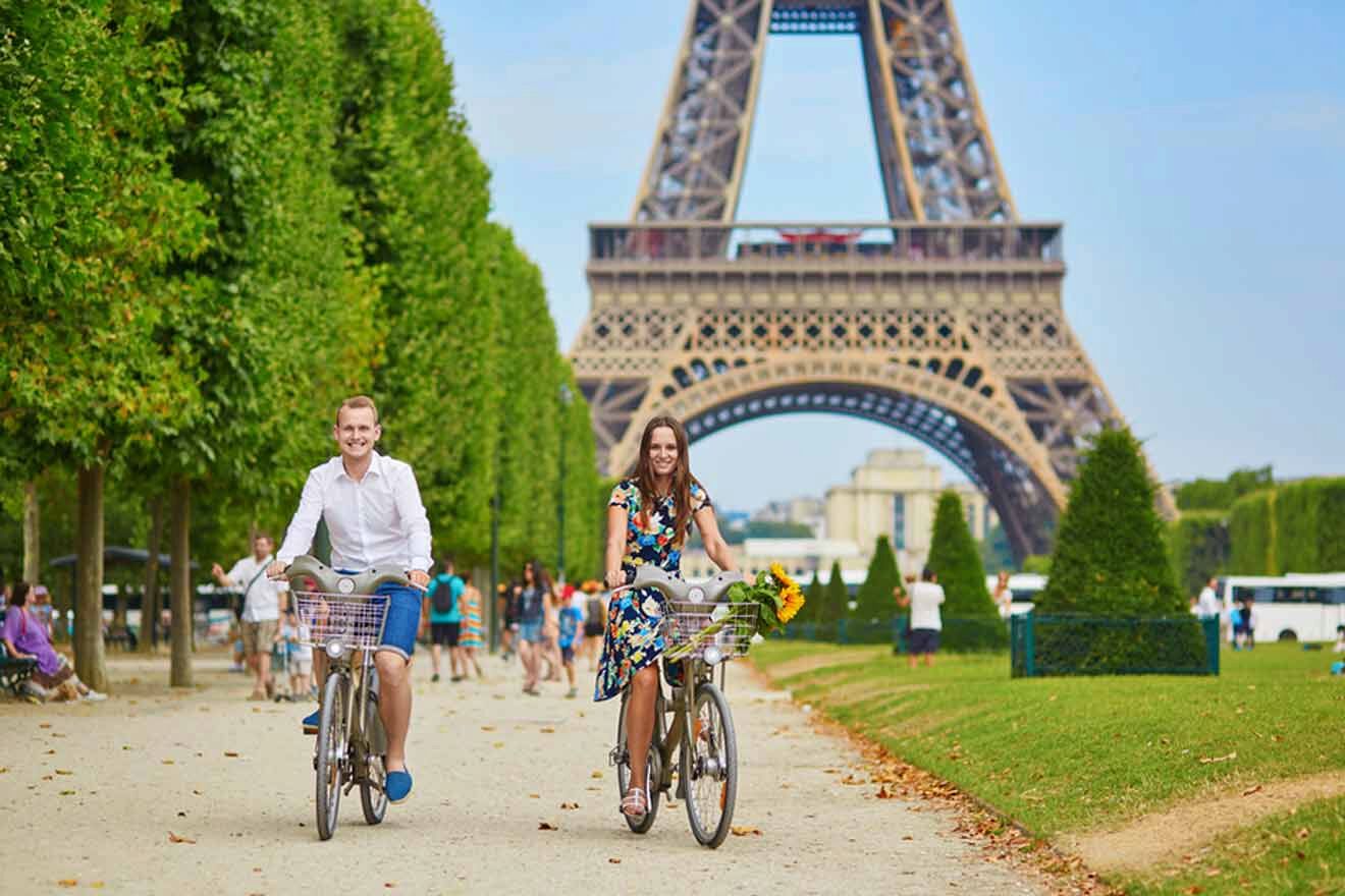 Two people riding bicycles in front of the eiffel tower.