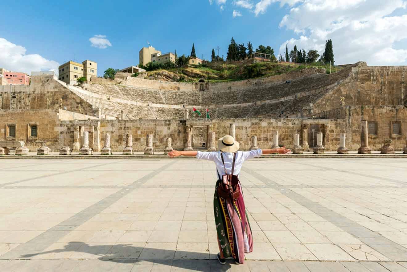 A woman is standing in front of an ancient amphitheater.
