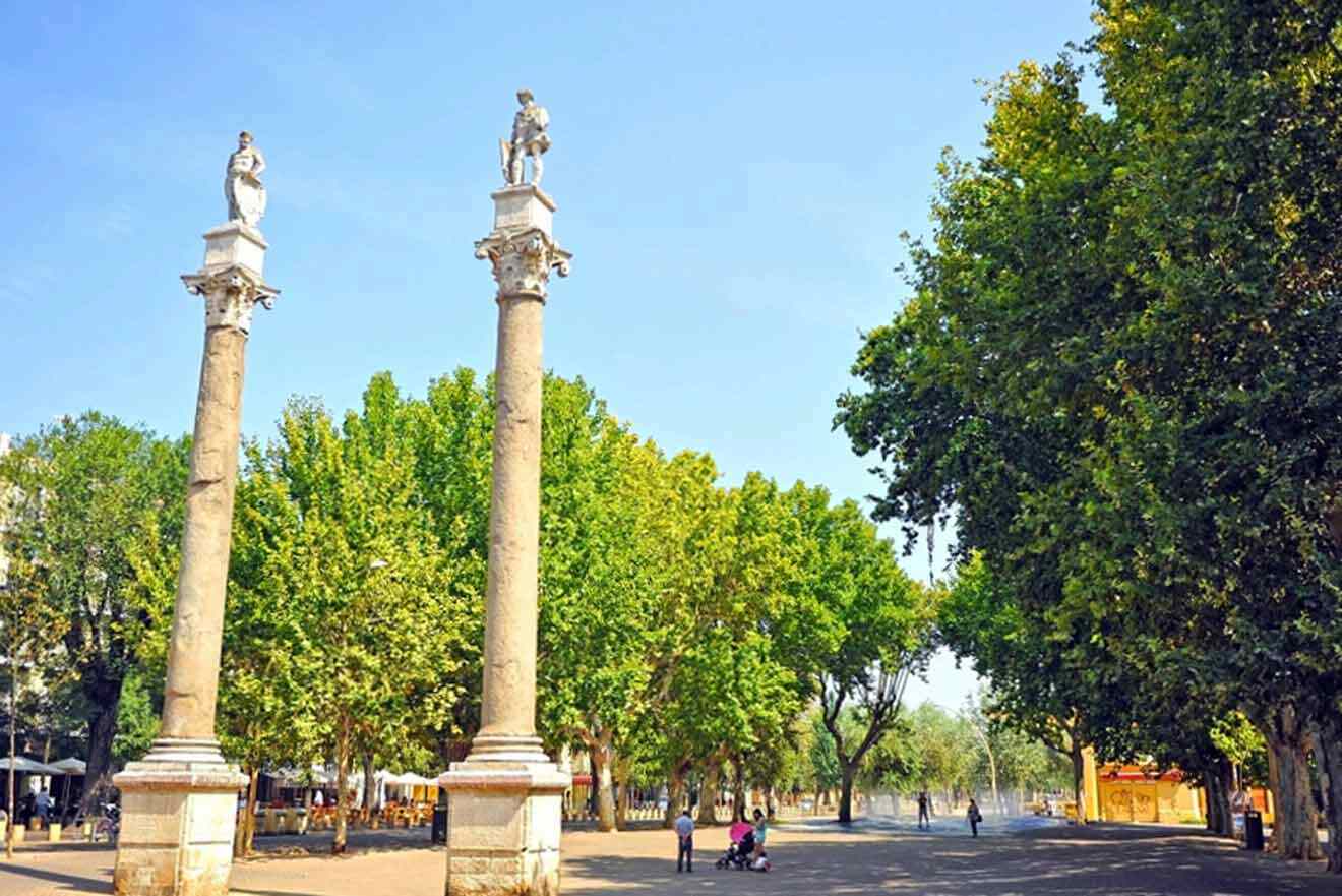 Two pillars in a park with trees in the background.