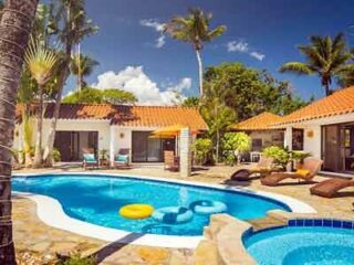 A villa with a swimming pool and lounge chairs.
