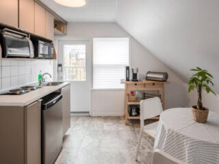 A small kitchen in an attic with a table and chairs.