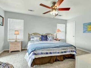 A bedroom with a ceiling fan and a bed.