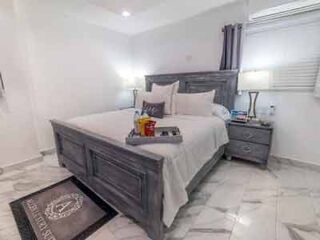 A bedroom with a white bed and marble floors.