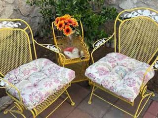 A pair of yellow wrought iron chairs on a patio.