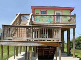 A beach house with stairs and a deck.