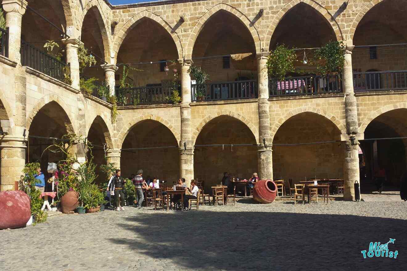 A courtyard with tables and chairs and arches.