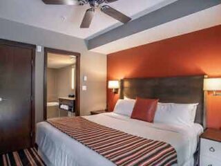 A hotel room with orange walls and a ceiling fan.
