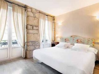 A white bed in a room with stone walls.