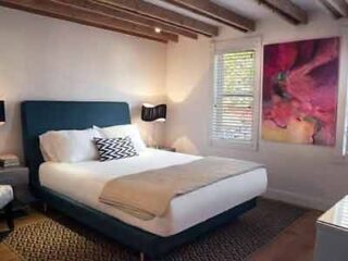 A bedroom with a bed and a painting on the wall.