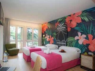 Two beds in a room with a tropical theme.