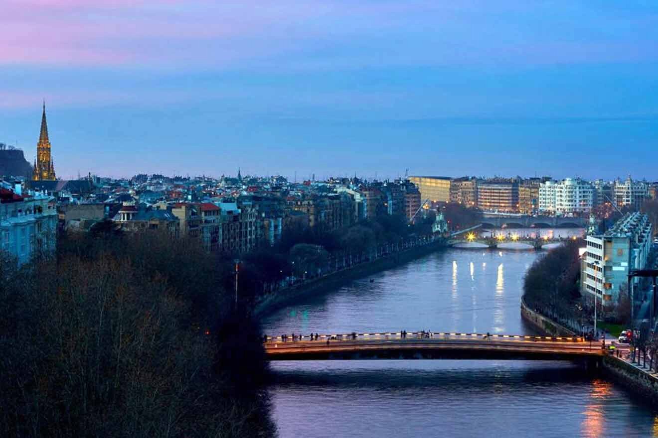 A bridge over a river in a city at dusk.