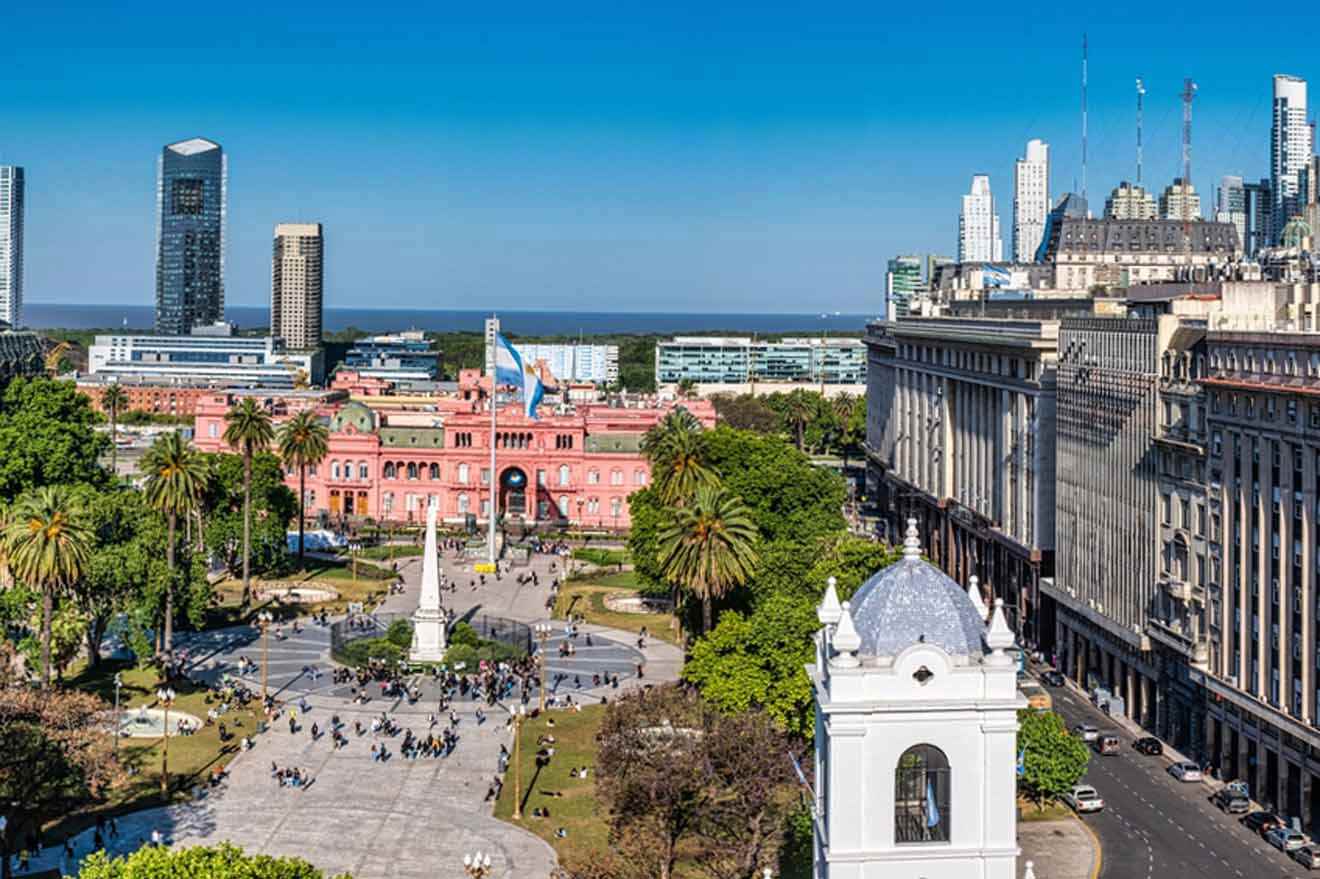 A view of Buenos Aires's Plaza de Mayo with lots of buildings and people walking around a monument