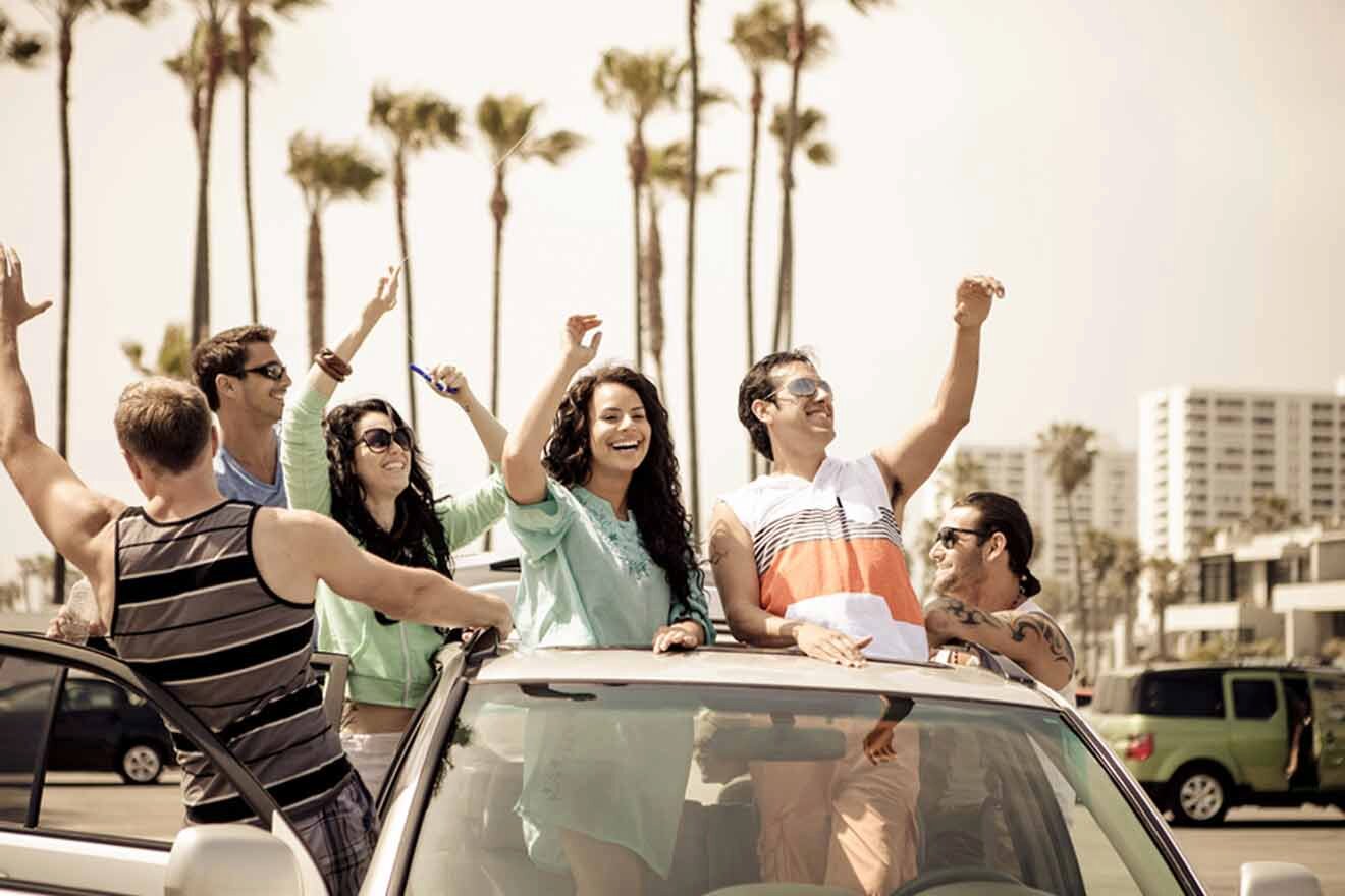 A group of people standing on top of a car and waving.