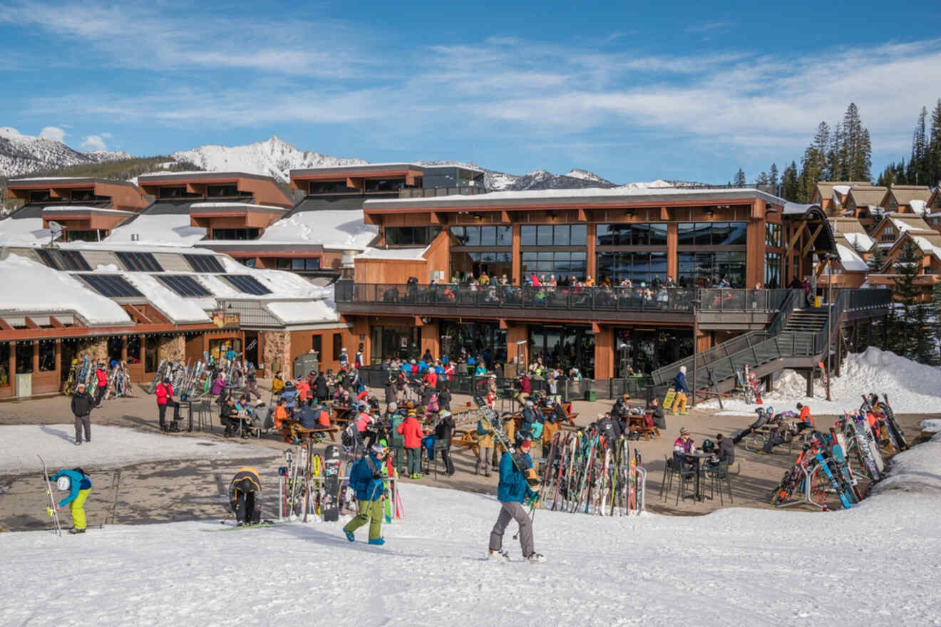 A group of skiers and snowboarders standing in front of a ski lodge.