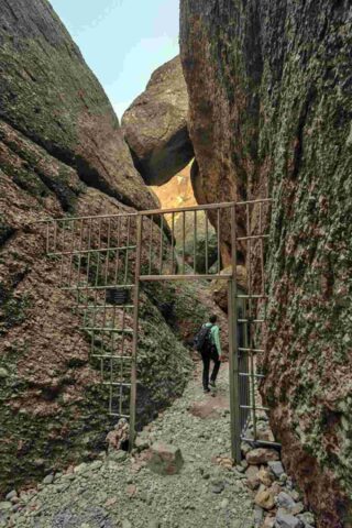 A man walking through a narrow passage surrounded by rocks