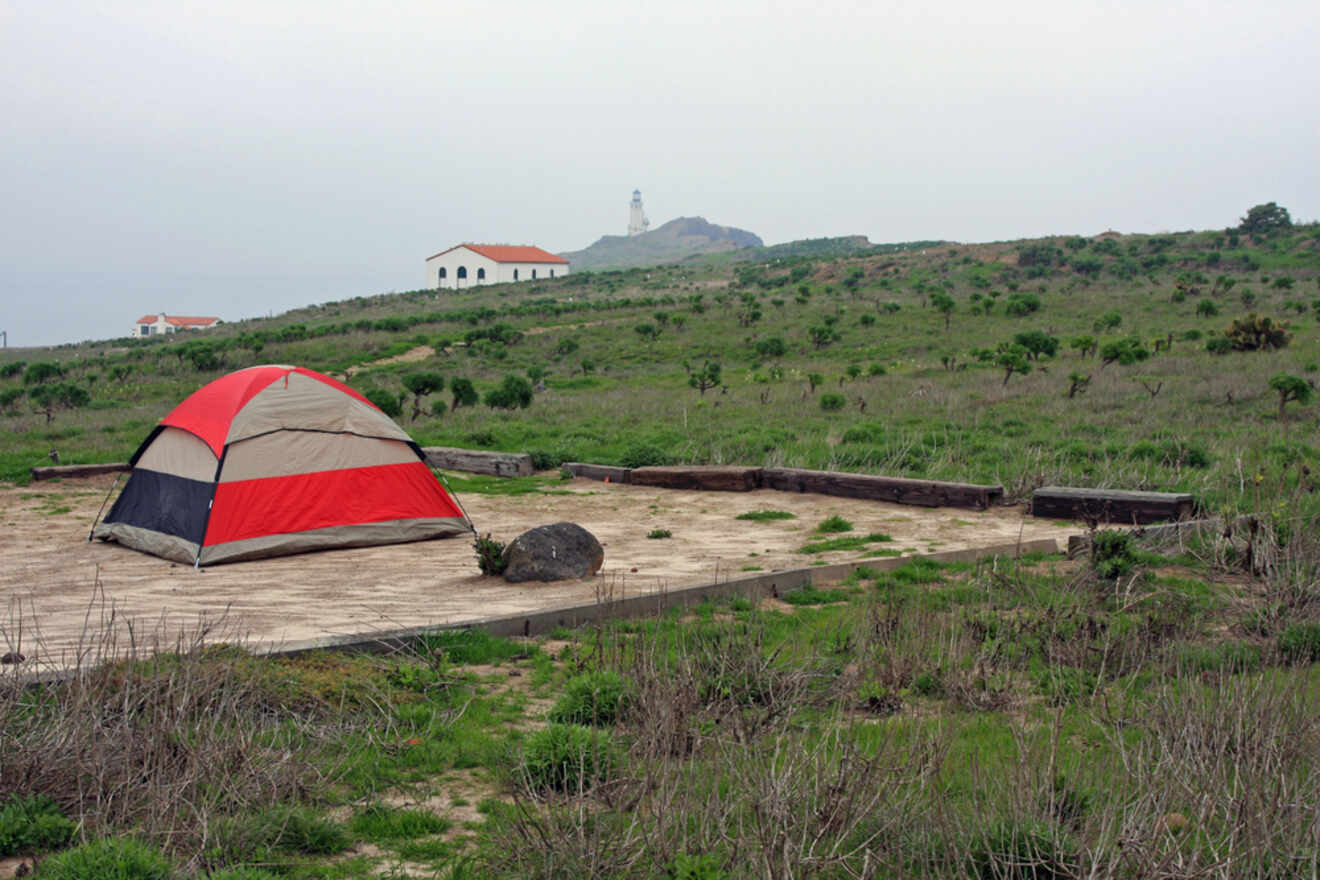 A tent set up in a grassy area with a lighthouse in the background.
