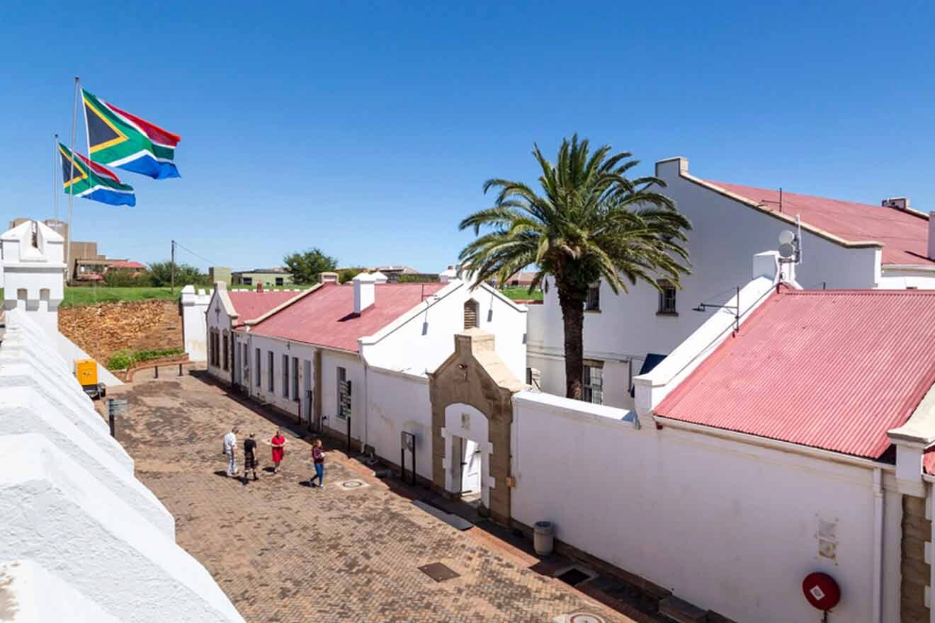 A view of a white building with a flag flying over it.