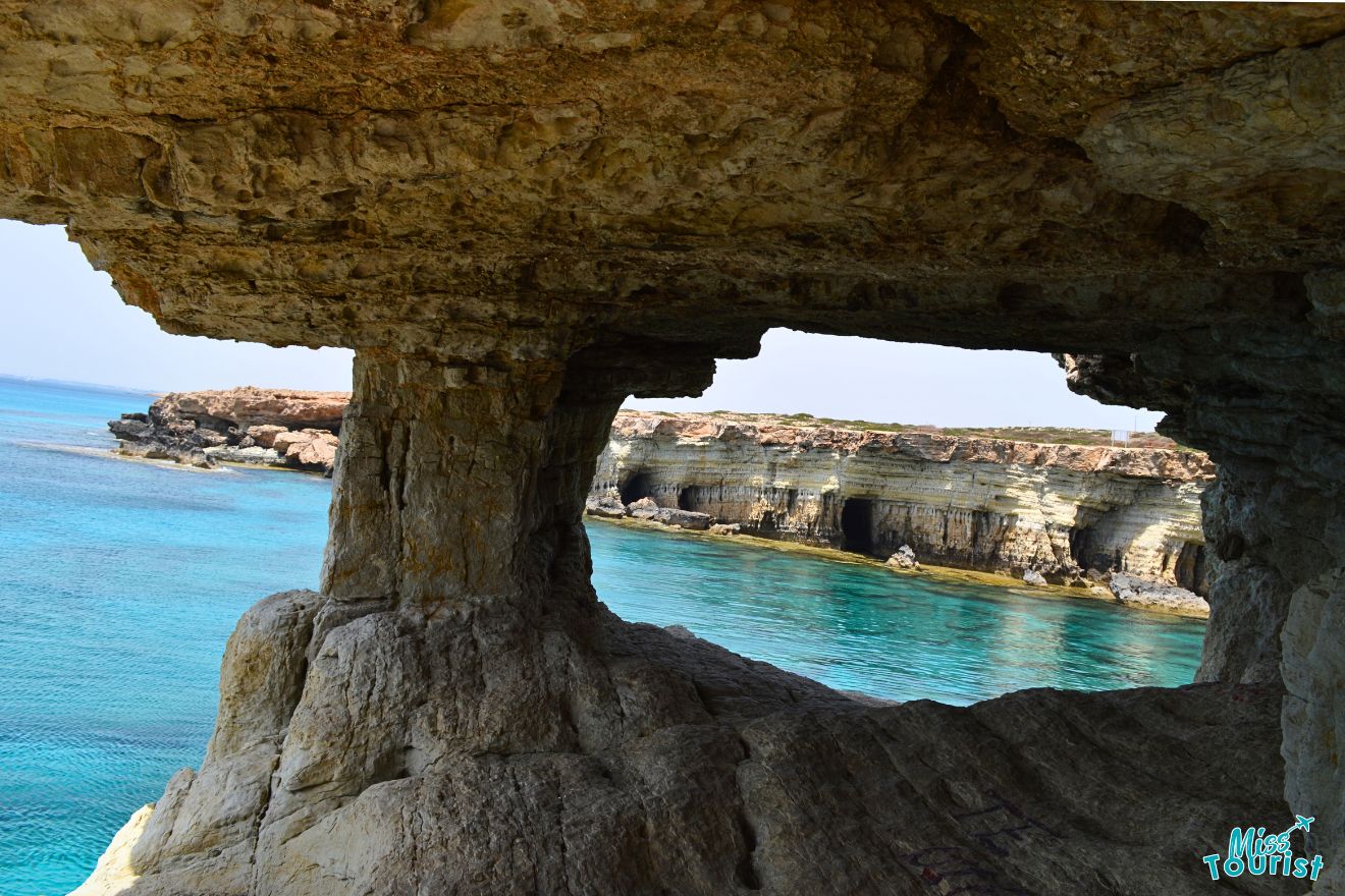 A cave with a view of the ocean and blue water.