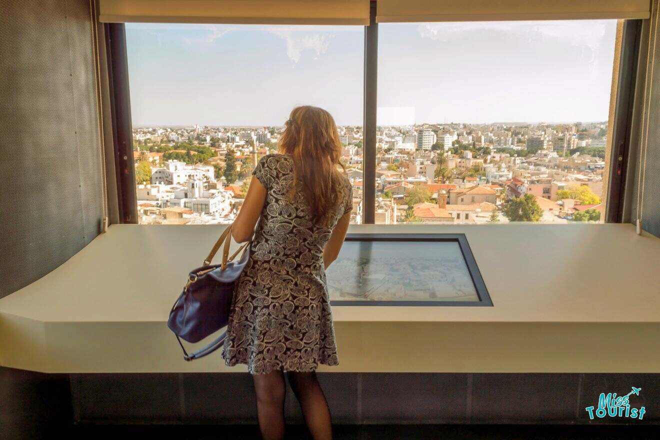 A woman looking out of a window at a city.