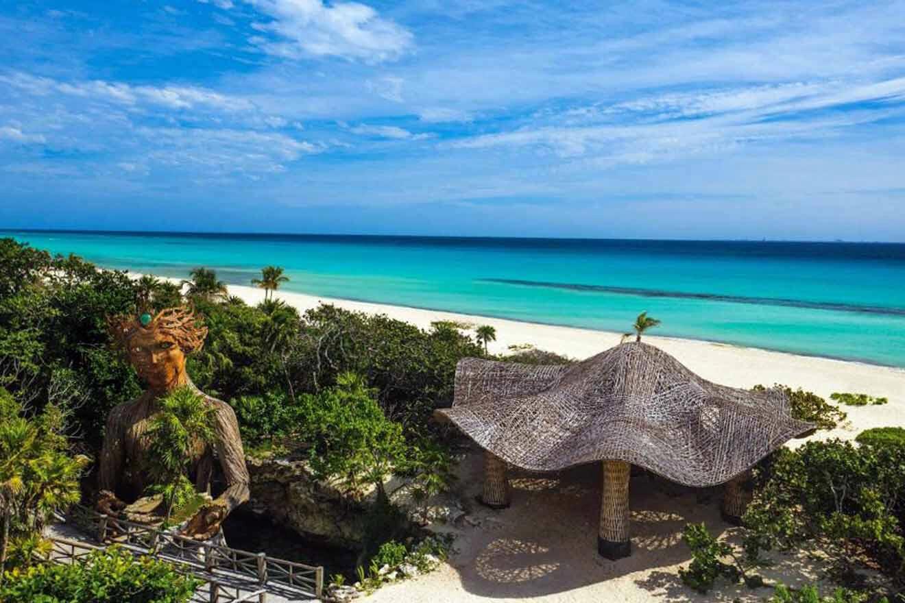 An aerial view of a beach with a hut and a statue.