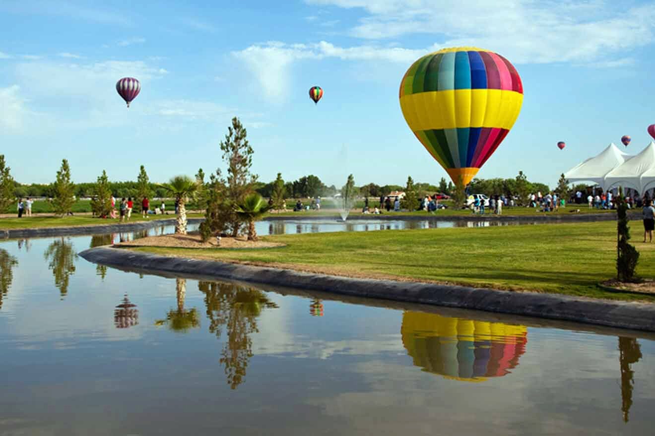 Hot air balloons flying over a pond.