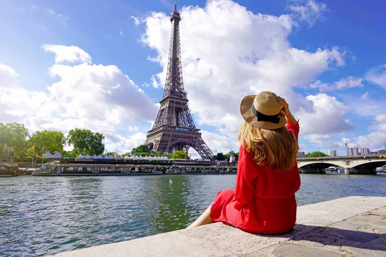 A woman in a red dress is looking at the eiffel tower.